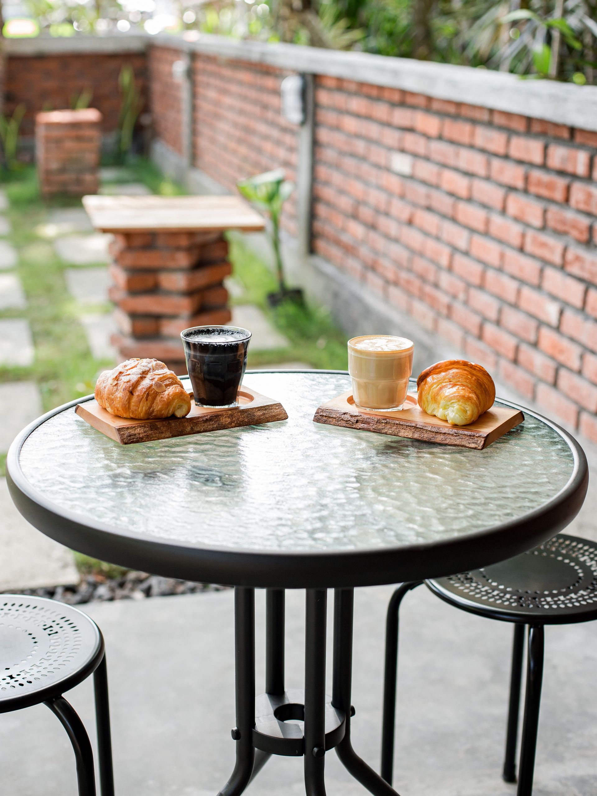 Relaxing outdoor café scene featuring coffee and croissants on a glass table, perfect for casual brunch vibes.
