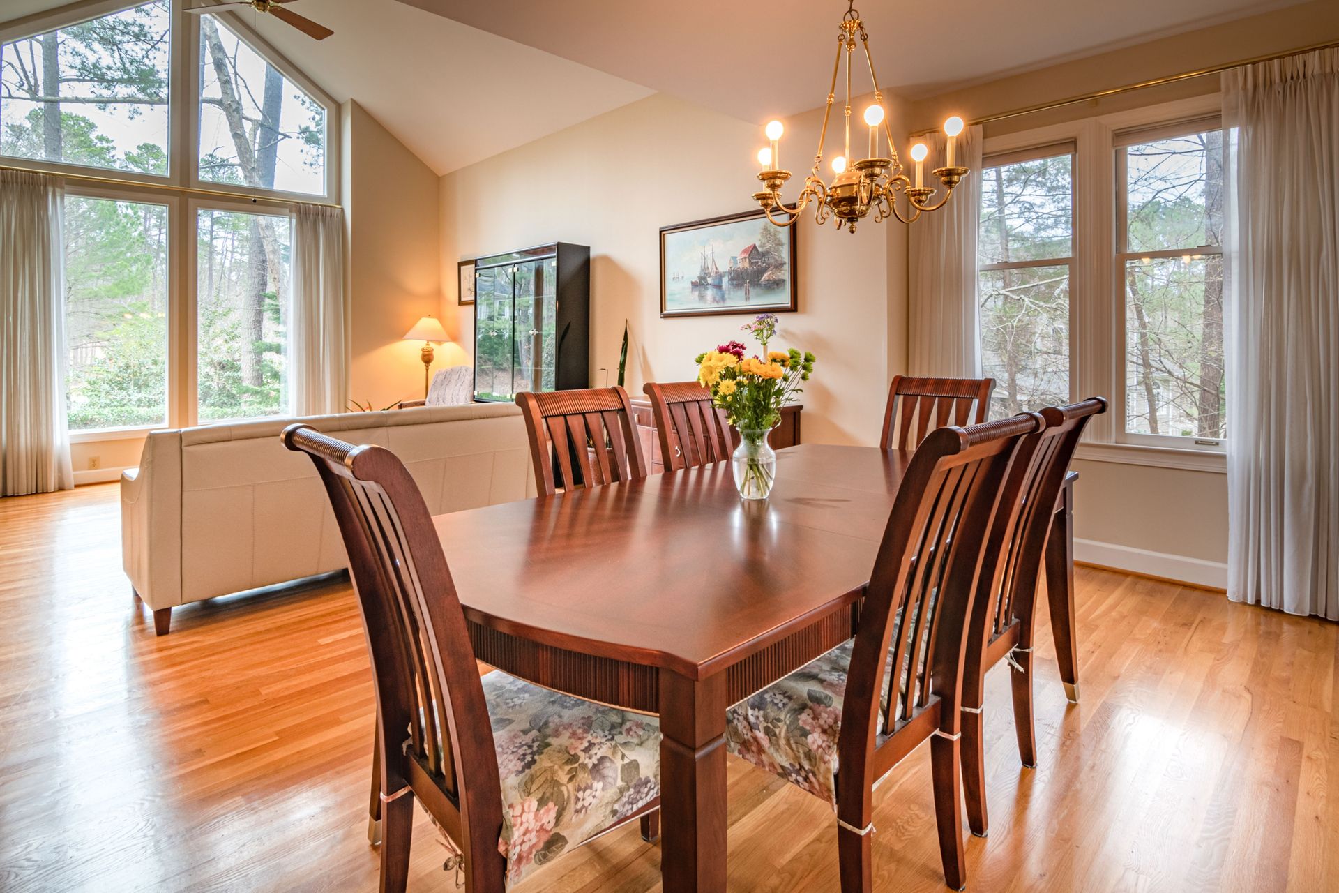 Bright indoor dining area showcasing dark wood furniture, large windows, and modern chandelier.