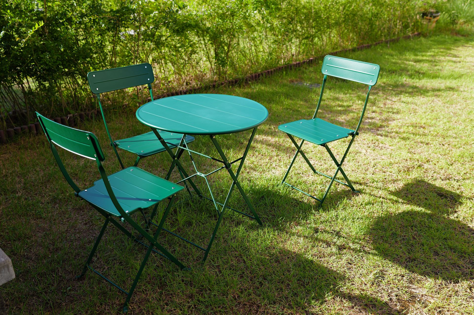 Bistro table and chairs set in a sunny garden with vibrant green surroundings.